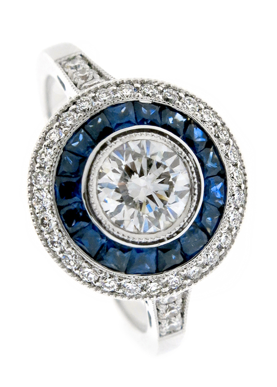 Round brilliant diamond bezel set in halo of custom cut sapphires and outeer halo of F VS round brilliant diamonds
